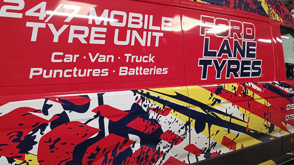 Indoor image of Ford Lane Tyres mobile tyre fitting van with bright red graphics and white and black signage