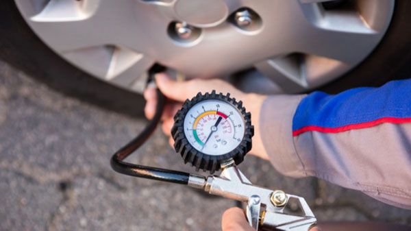 Image shows somebody measuring their tyre pressure using a car tyre pressure gauge