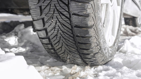 Outdoor image showing a car tyre and its tread depth parked on the snow in winter in the UK